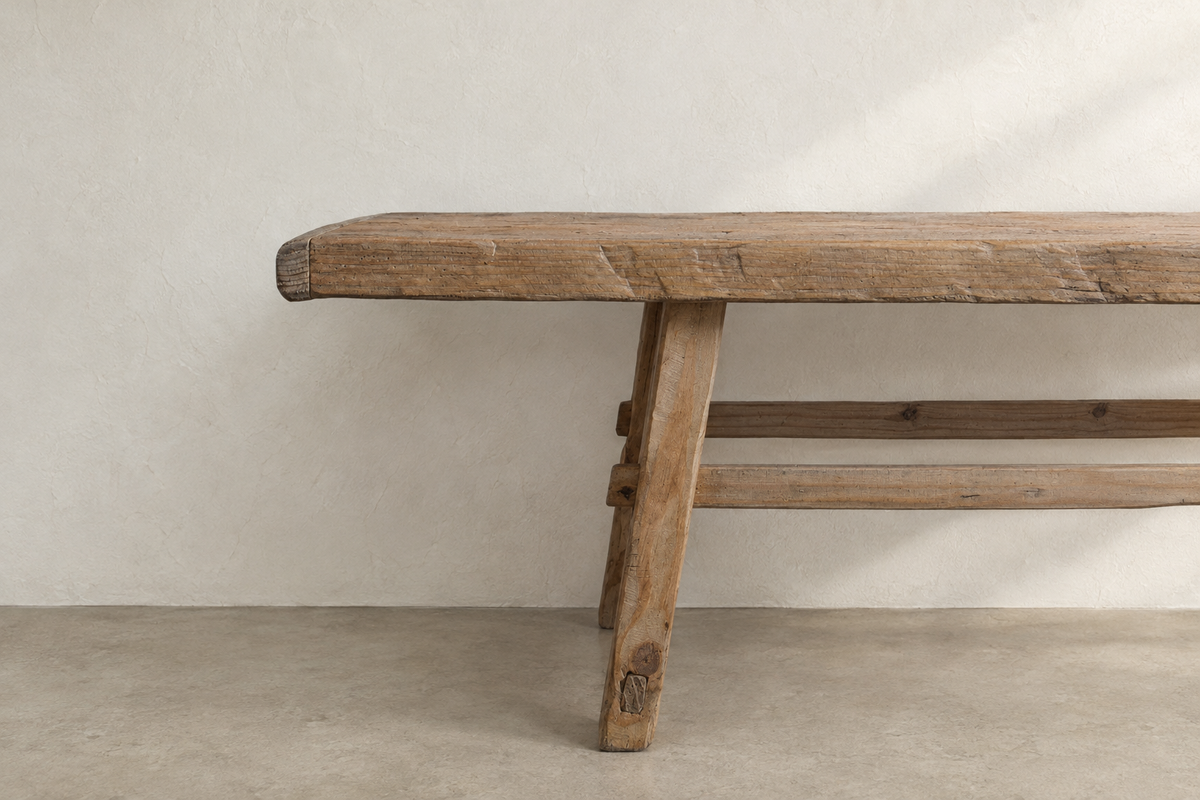 Solid wood Longhouse Bench featuring angled supports, a narrow seat, and an aged pine finish.