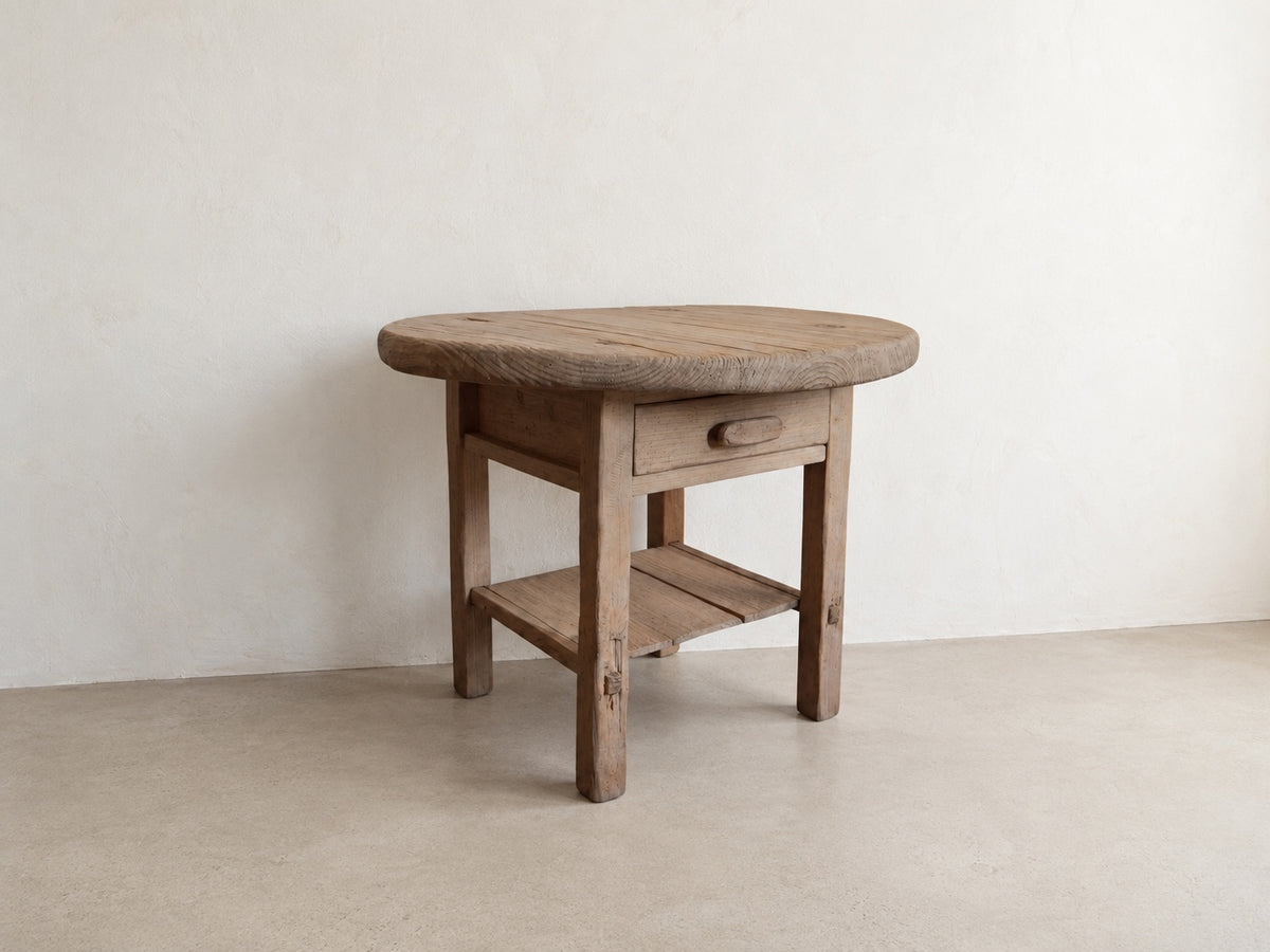     Three-quarter view of The Cooper Table showing its round top, storage drawer, and open lower shelf