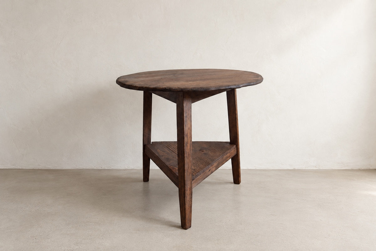 Three-quarter view of The Cricket Table showing its round top, three-leg base, and triangular lower shelf