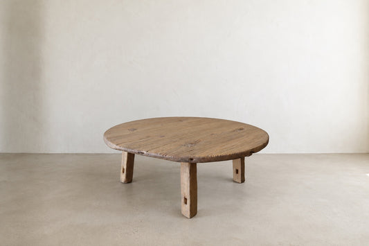 Angled view of The Croft Coffee Table showing its round top and natural aged wood grain