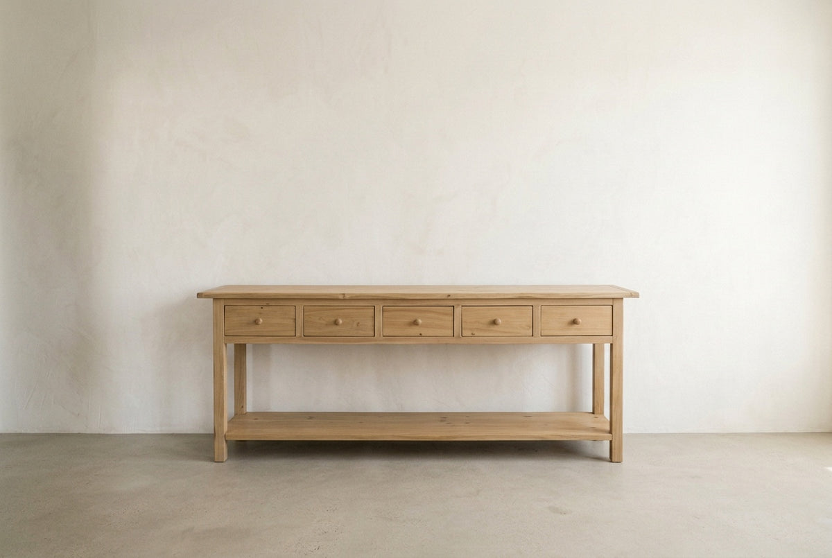 Straight-on studio view of the Mercantile five-drawer console table in a neutral plaster setting
