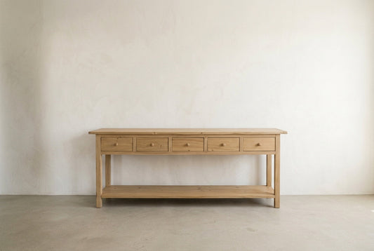 Straight-on studio view of the Mercantile five-drawer console table in a neutral plaster setting