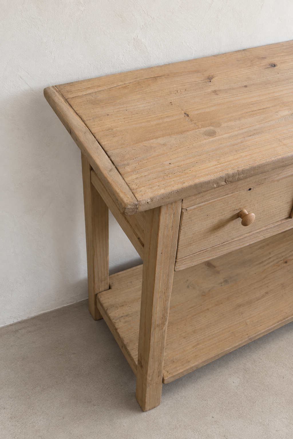 Close-up angled detail of the Mercantile console tabletop, drawer, leg, and lower shelf showing natural wood grain and joinery
